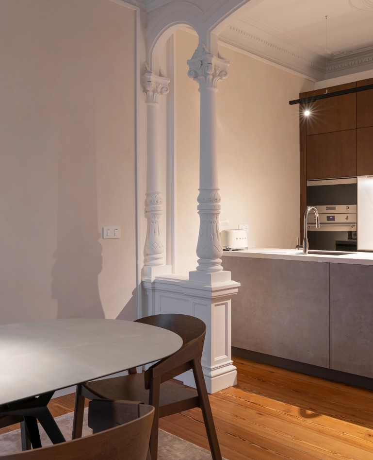 Arcos decorativos blancos que separan el comedor de la cocina con isla gris.