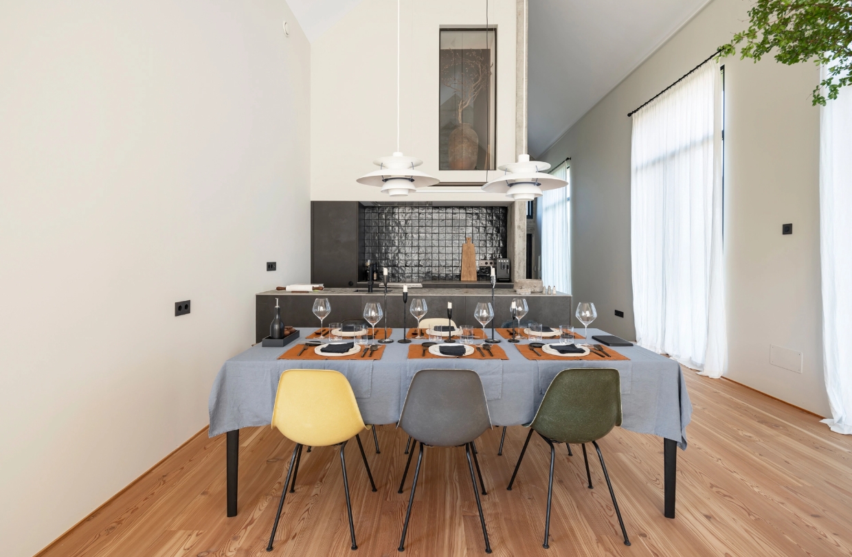 Rectangular dining table with blue tablecloth and Nordic style chairs in front of modern kitchen.