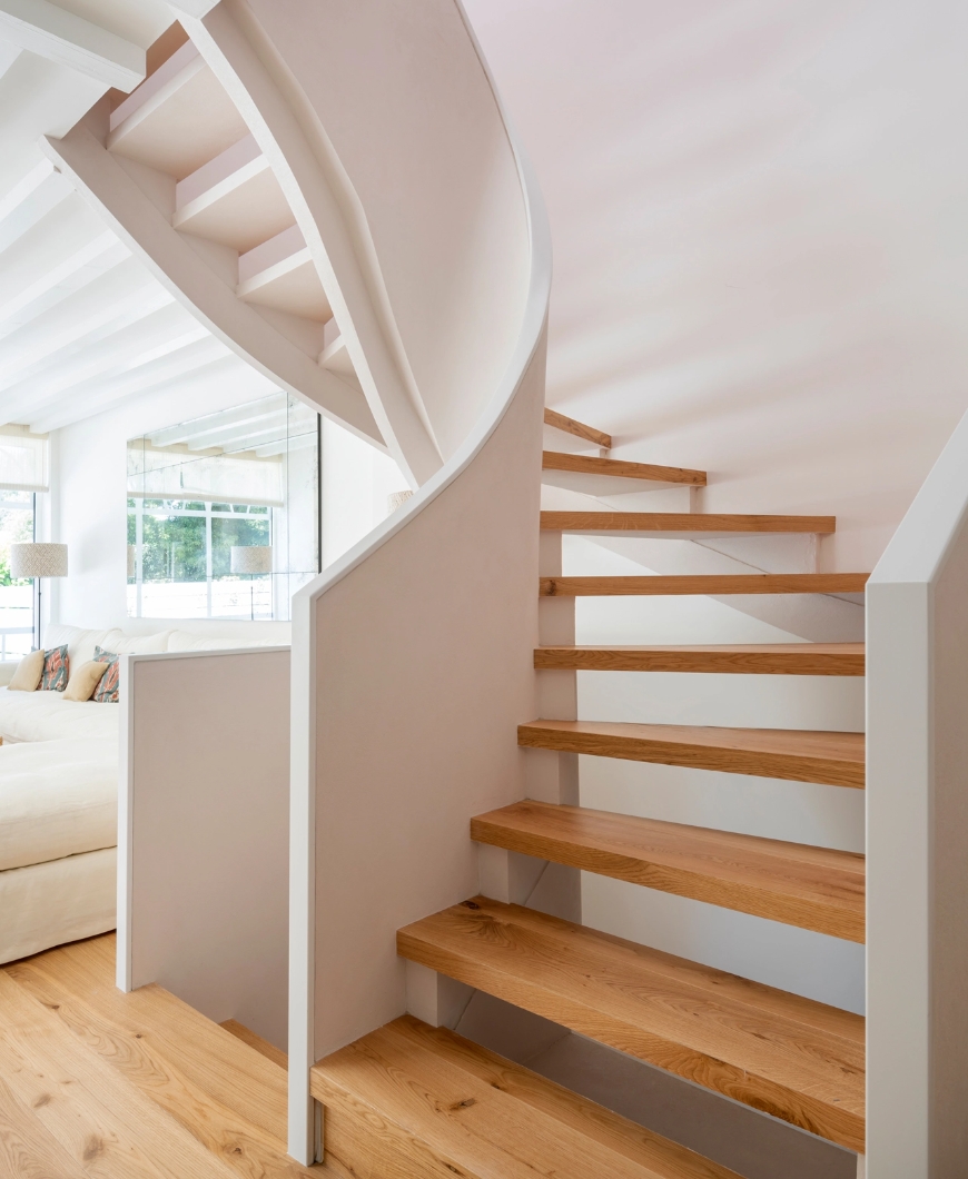 Modern spiral staircase with light wood steps and white structure in minimalist living room.