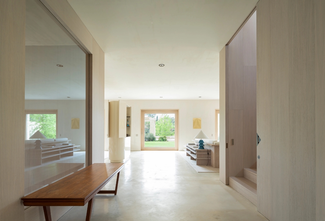 Spacious hallway with polished concrete floors, wooden bench and views to the living room and garden.