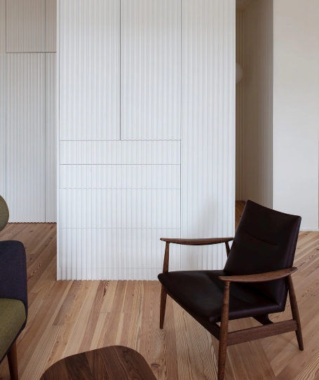 Dark leather armchair in front of white slatted paneled cabinet