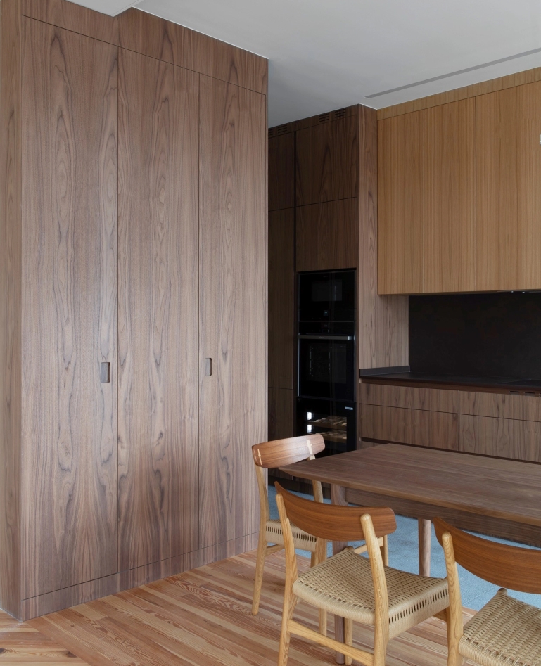 Open kitchen with wooden cabinets, black appliances and dining table.