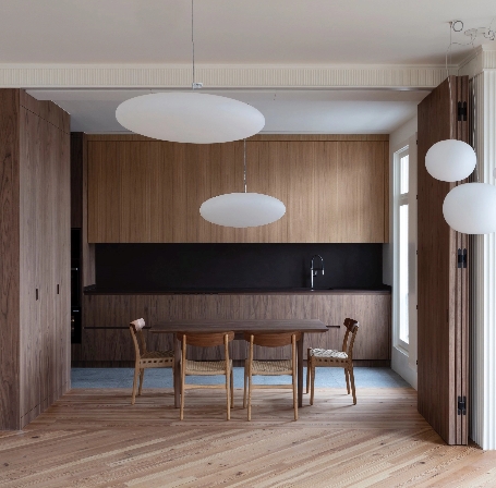 Dining room with white circular ceiling lamps and natural wood furniture.