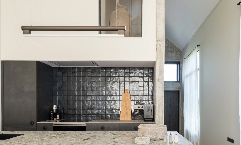 Modern kitchen with dark gray island, stone countertop and glossy black tile front.