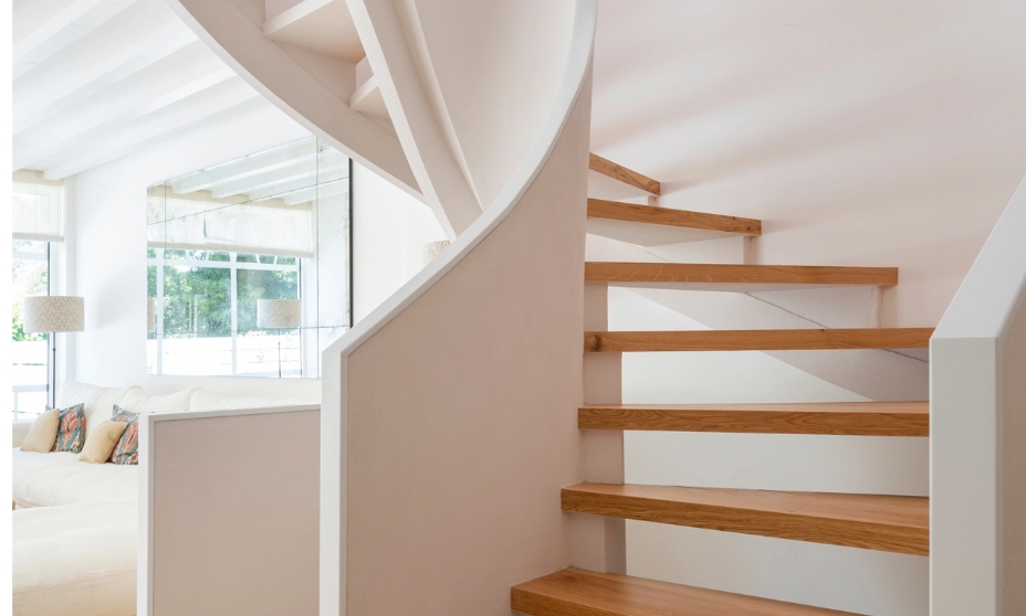 Modern spiral staircase with light wood steps and white structure in minimalist living room.