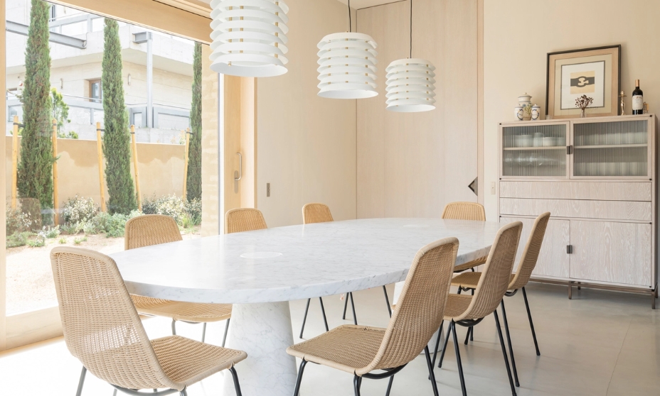 Bright dining room with oval table, wicker chairs and three white designer lamps.