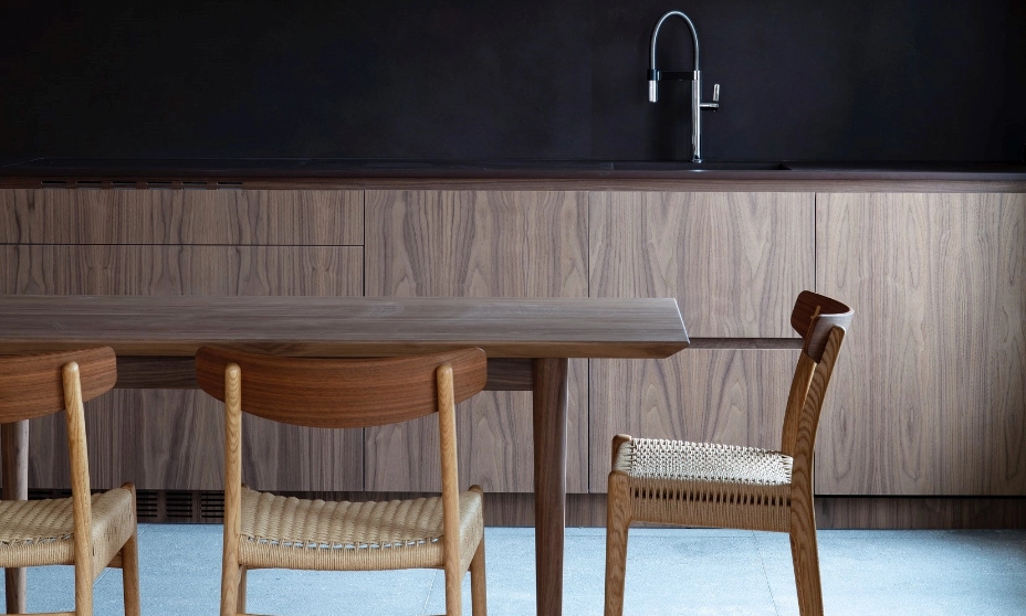 Minimalist kitchen with wooden furniture, black countertop wall and dining table.