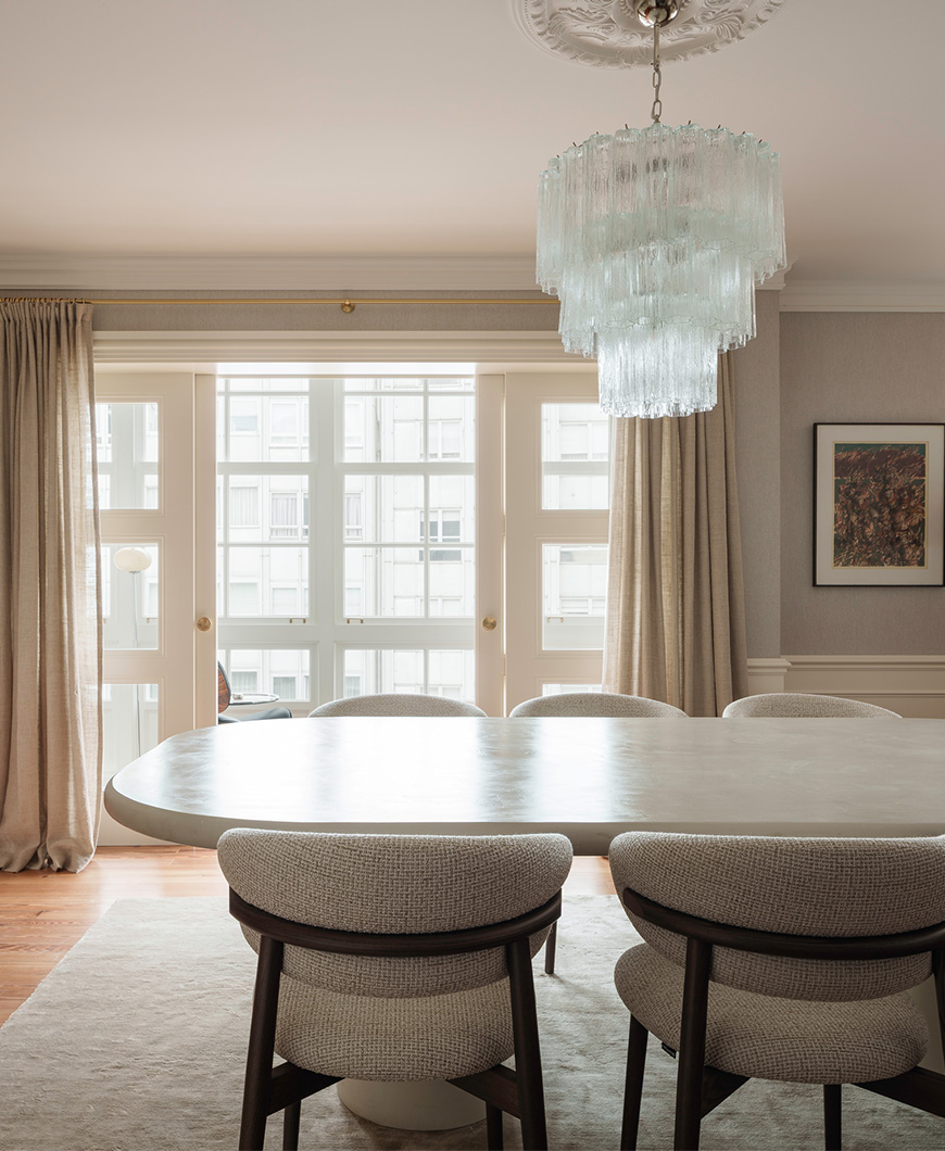 Elegante comedor con una mesa ovalada, sillas tapizadas modernas y una lámpara de cristal espectacular arriba.