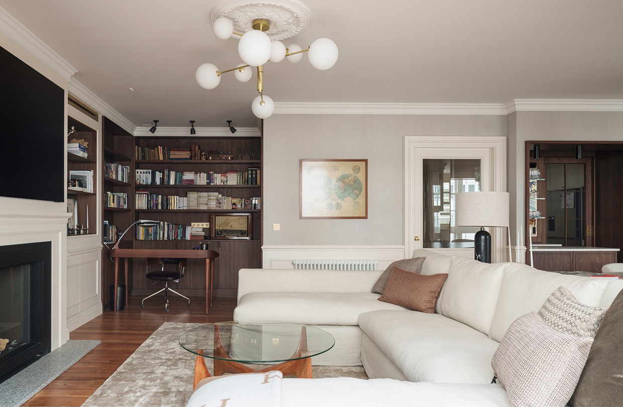 Amplio salón con sofá cómodo, estanterías repletas de libros, chimenea y una mesa de centro circular baja.