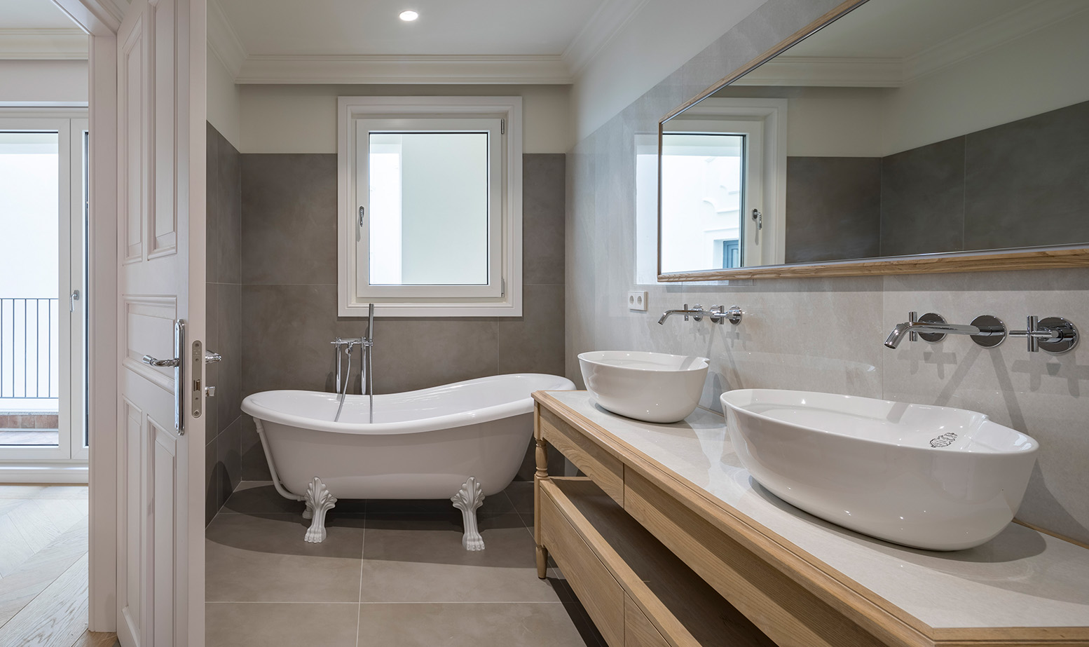 Cuarto de baño clásico con bañera antigua, doble lavabo y acabados en tonos muy neutros.