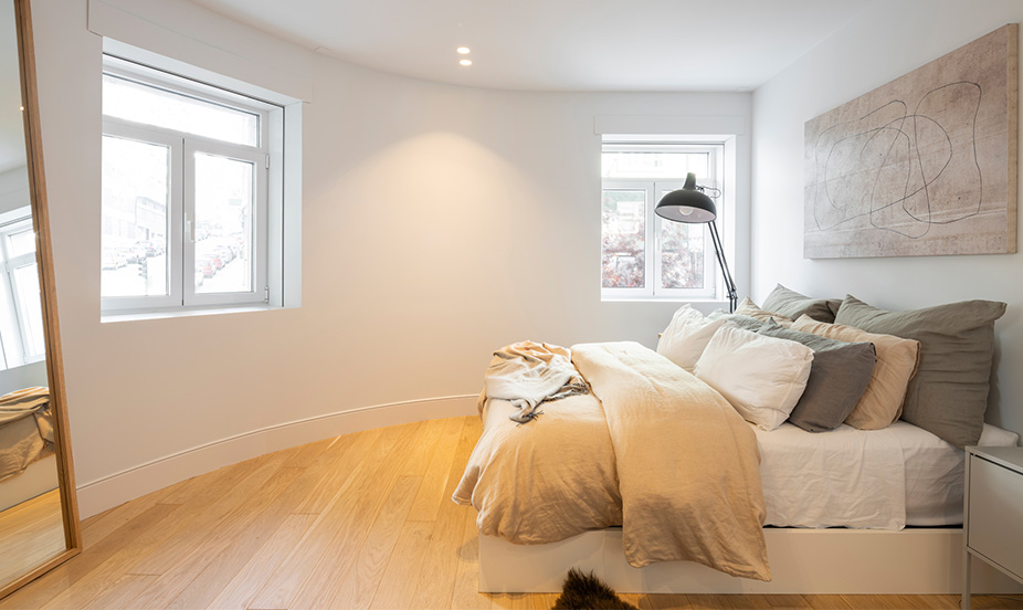 Serene and minimalist bedroom that stands out for its natural wood floor, with a cozy and very bright atmosphere.