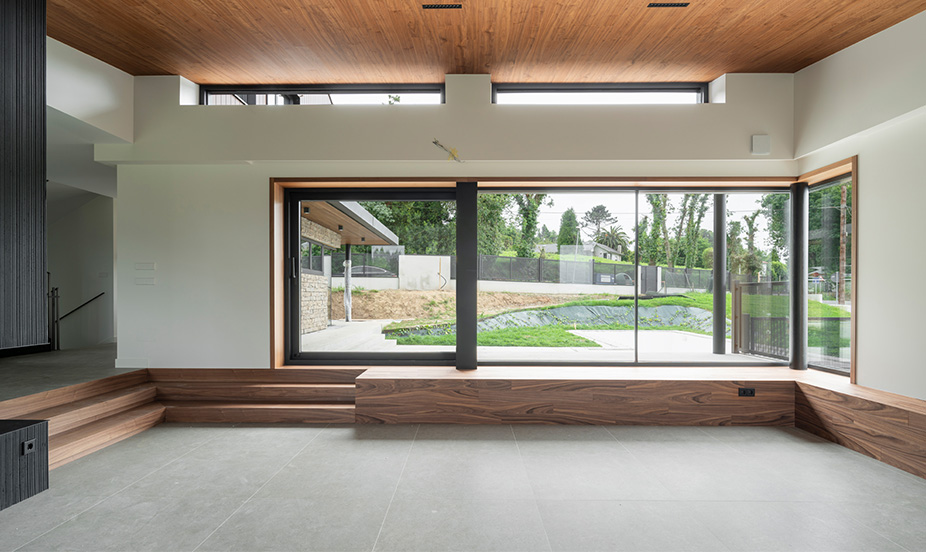 Modern interior with large gray floors, wooden ceilings and a large window overlooking the garden.