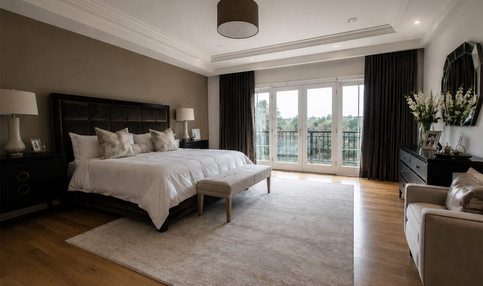 An elegant master bedroom with earth-toned walls, dark curtains, and large glass doors leading to a balcony.