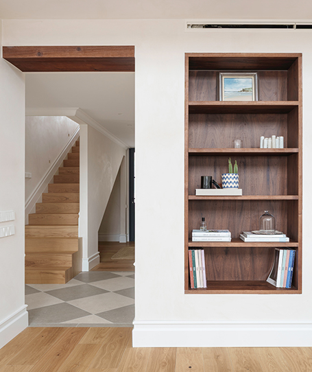 A custom-made, dark-wood bookshelf built into the wall of the living room in a single-family home.