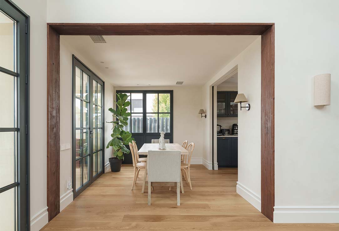 Dining room in a single-family home with hardwood floors, white interior trim, and a doorway frame clad in dark wood.