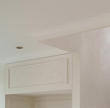 Close-up of custom interior woodwork featuring decorative moldings and white-lacquered paneling.